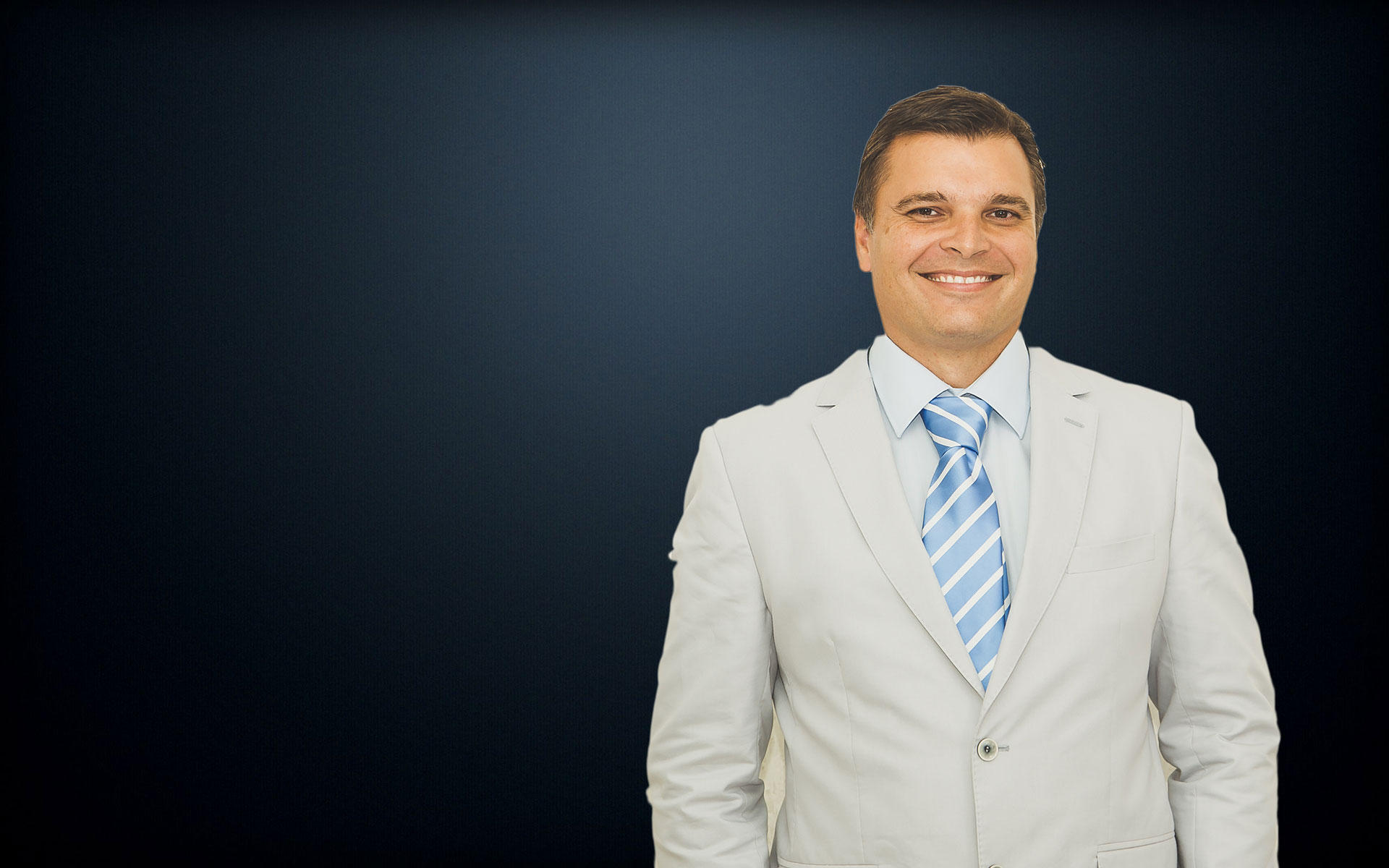 Dr Johan Blignaut dressed in a light formal suit with blue tie, smiling.